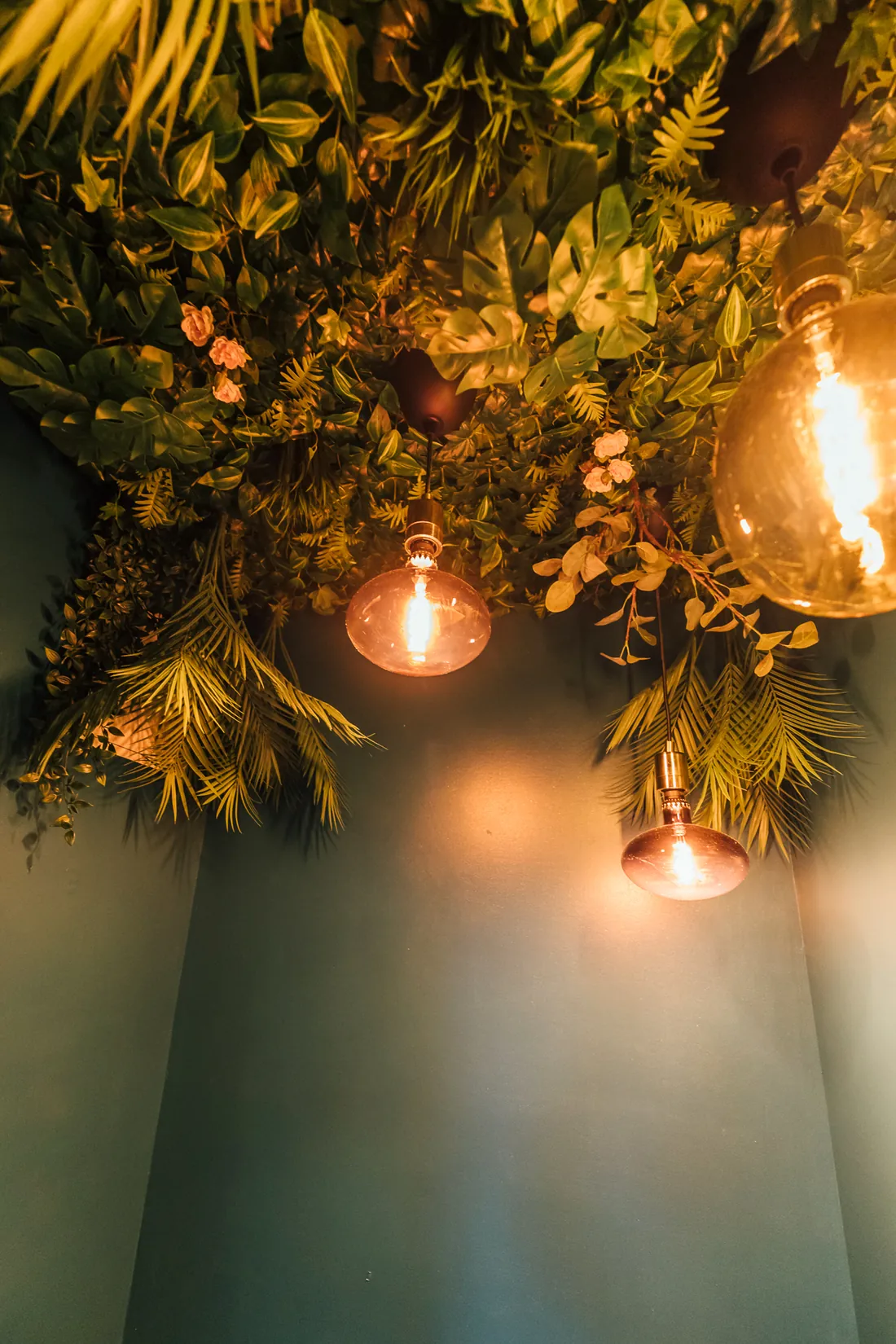 Begrünte Decke mit goldenen Pendelleuchten
